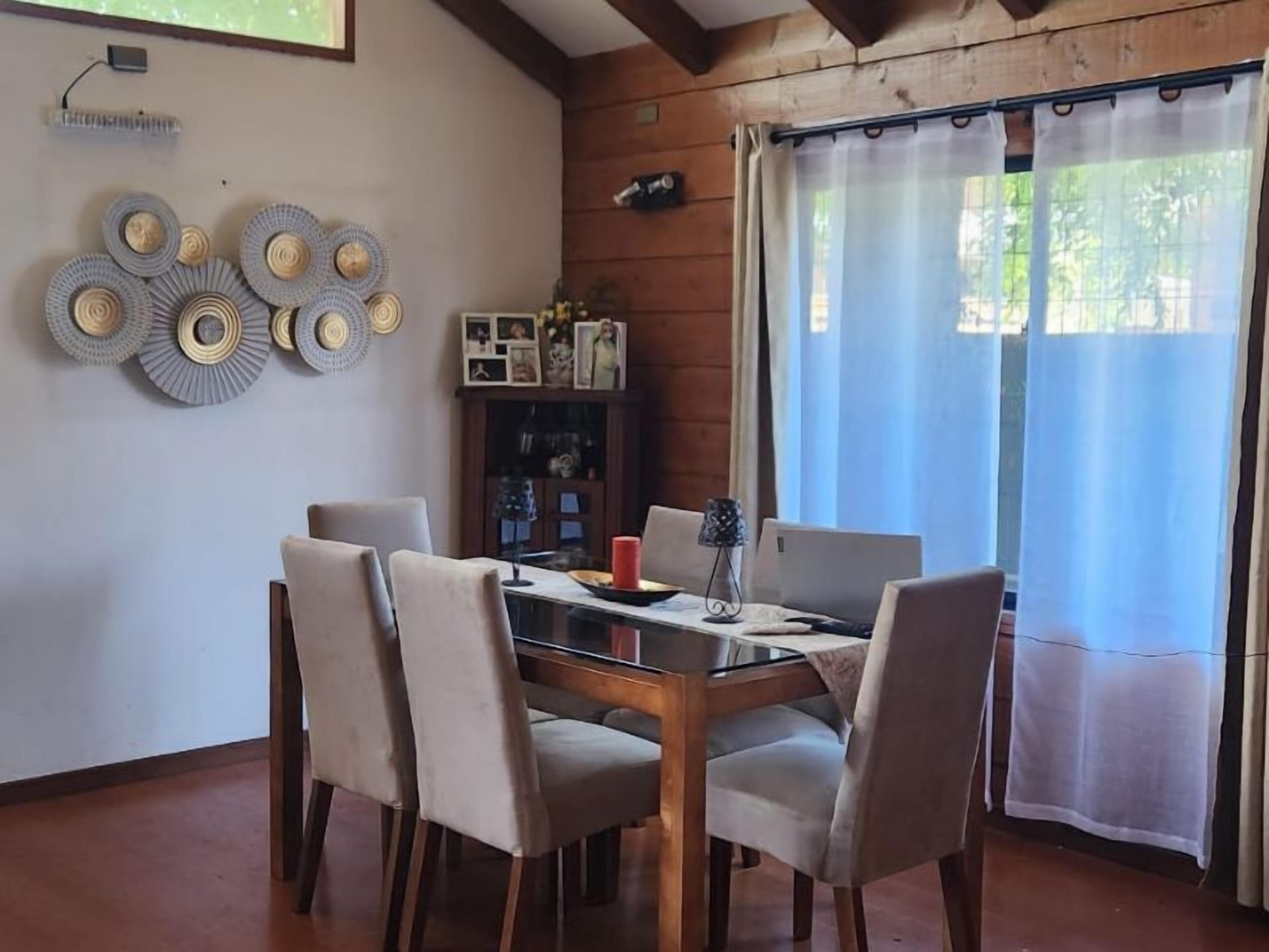 Un coin repas avec une table et des chaises en bois, un ordinateur portable et un élément décoratif mural.