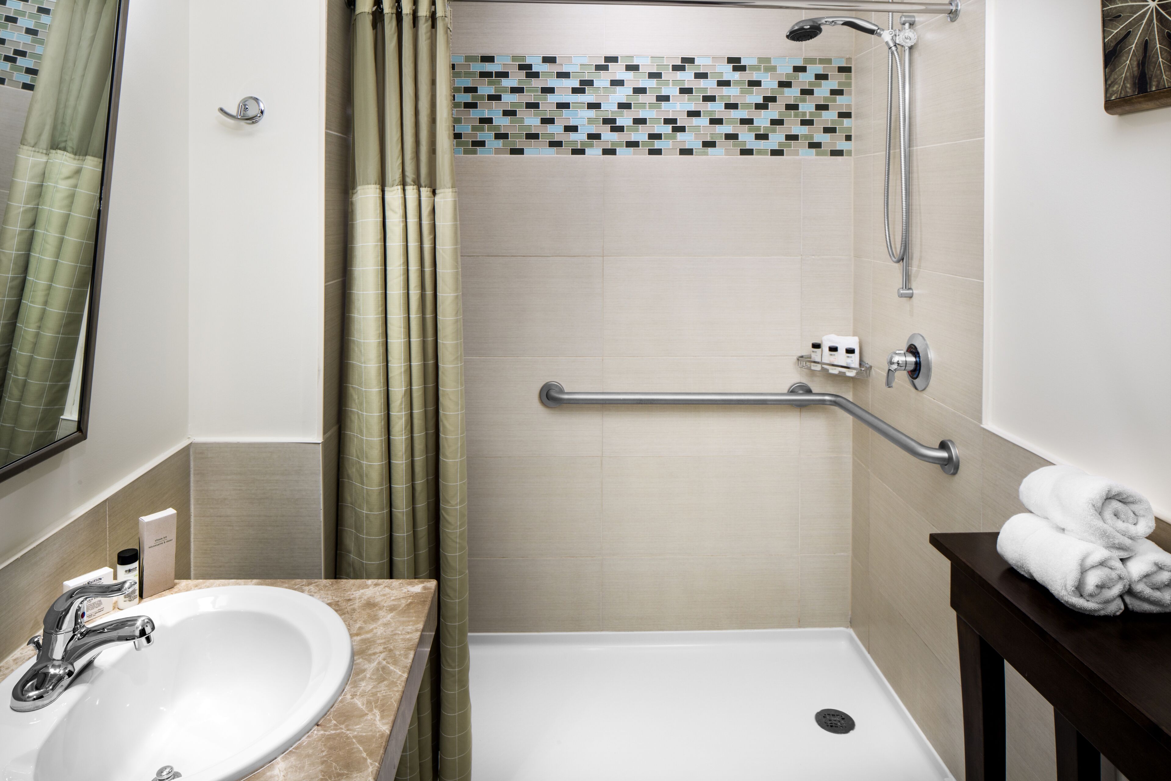 A bathroom with a sink, shower, and a towel rack.