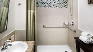 A bathroom with a sink, shower, and a towel rack.