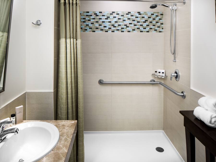 A bathroom with a sink, shower, and a towel rack.
