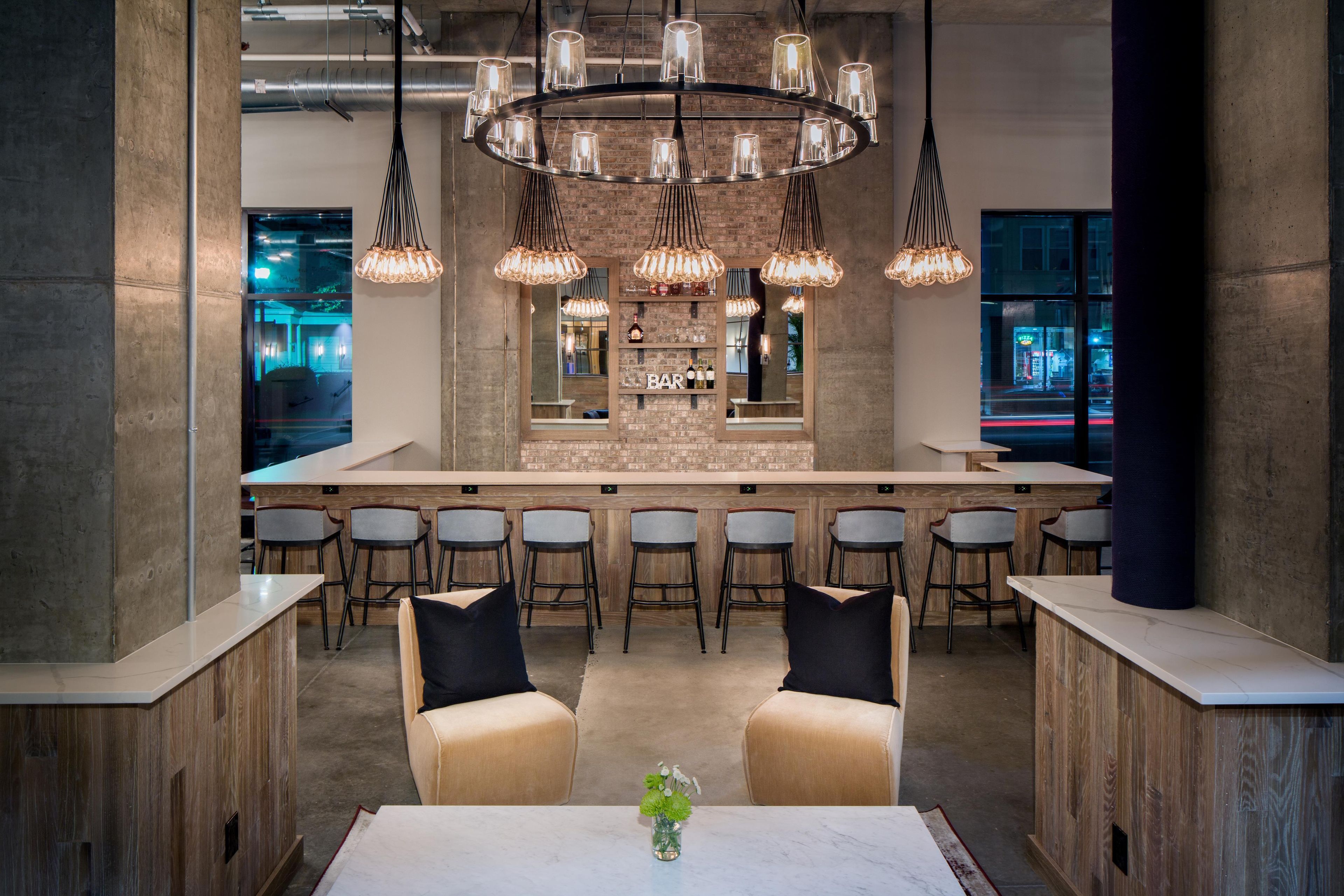 A modern bar area with a central island, bar stools, and a seating area with two sofas.