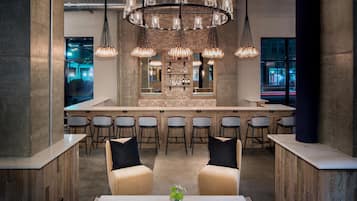 A modern bar area with a central island, bar stools, and a seating area with two sofas.