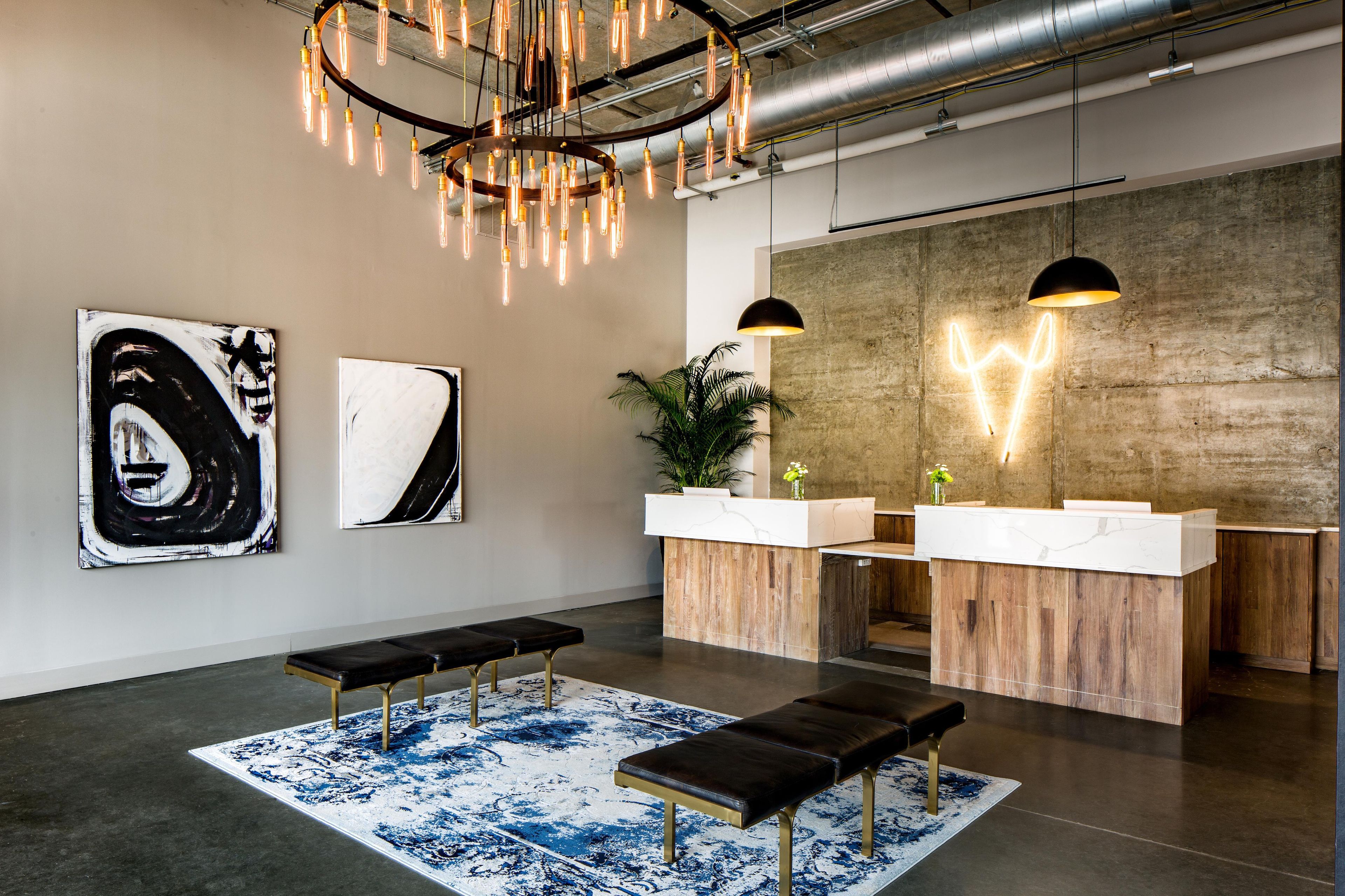 A modern reception area with a wooden counter, two pendant lights, and artwork on the walls.