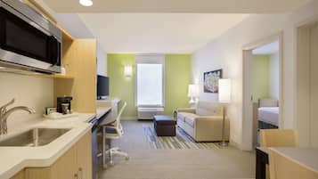 Une chambre d’hôtel compacte comprenant un coin cuisine, un canapé, un bureau et un lit.