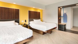 A modern hotel room with two beds, wooden headboards, and a small bedside table with a lamp. - Tru by Hilton Cheyenne WY (Cheyenne)