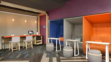 A modern hotel room with a desk, two chairs, a sofa, and a small table.