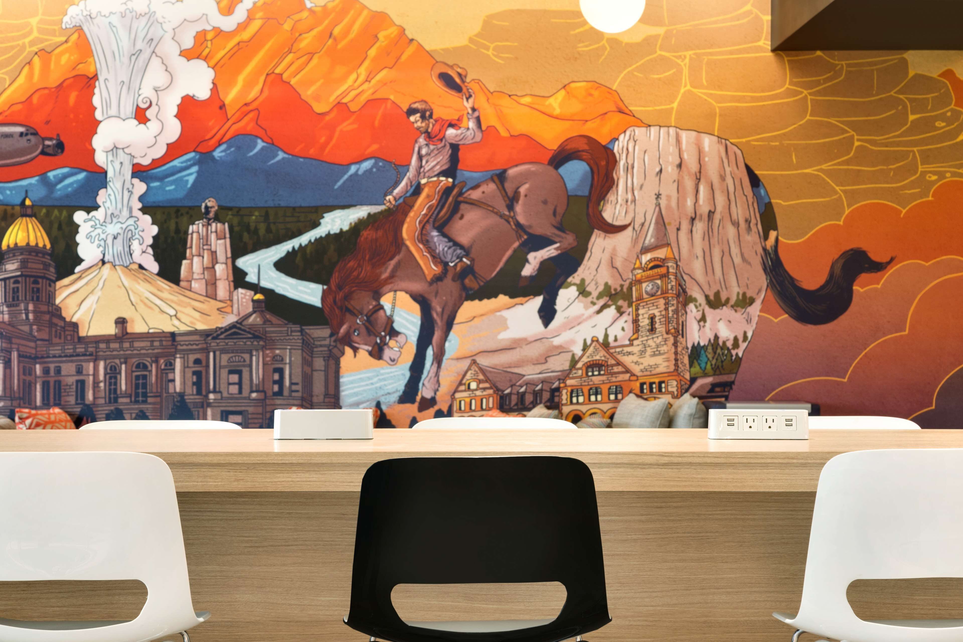 A reception desk with a mural depicting a man on a horse, a volcano, and buildings.