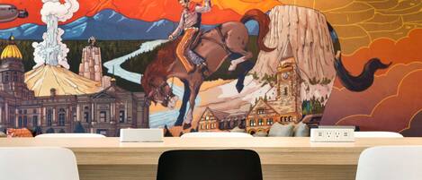 A reception desk with a mural depicting a man on a horse, a volcano, and buildings.