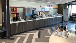 A self-service breakfast bar with coffee machines, milk dispensers, and a variety of toppings.