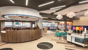 A modern reception area with a wooden reception desk, seating area with sofas, and a coffee station.
