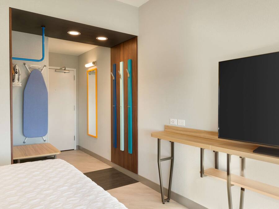 Quarto de hotel moderno com uma cama, uma TV de tela plana, uma escrivaninha de madeira e um espelho.
