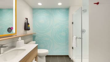 A modern bathroom with a white sink, toilet, and glass shower enclosure.