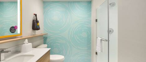Een moderne badkamer met een wit wastafelmeubel, toilet en douchecabine met glazen wanden.