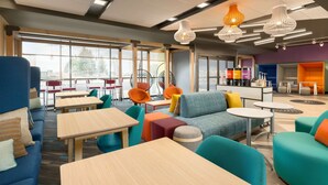 A modern indoor space with seating areas, tables, and a bar area. - Tru by Hilton Cheyenne WY (Cheyenne)