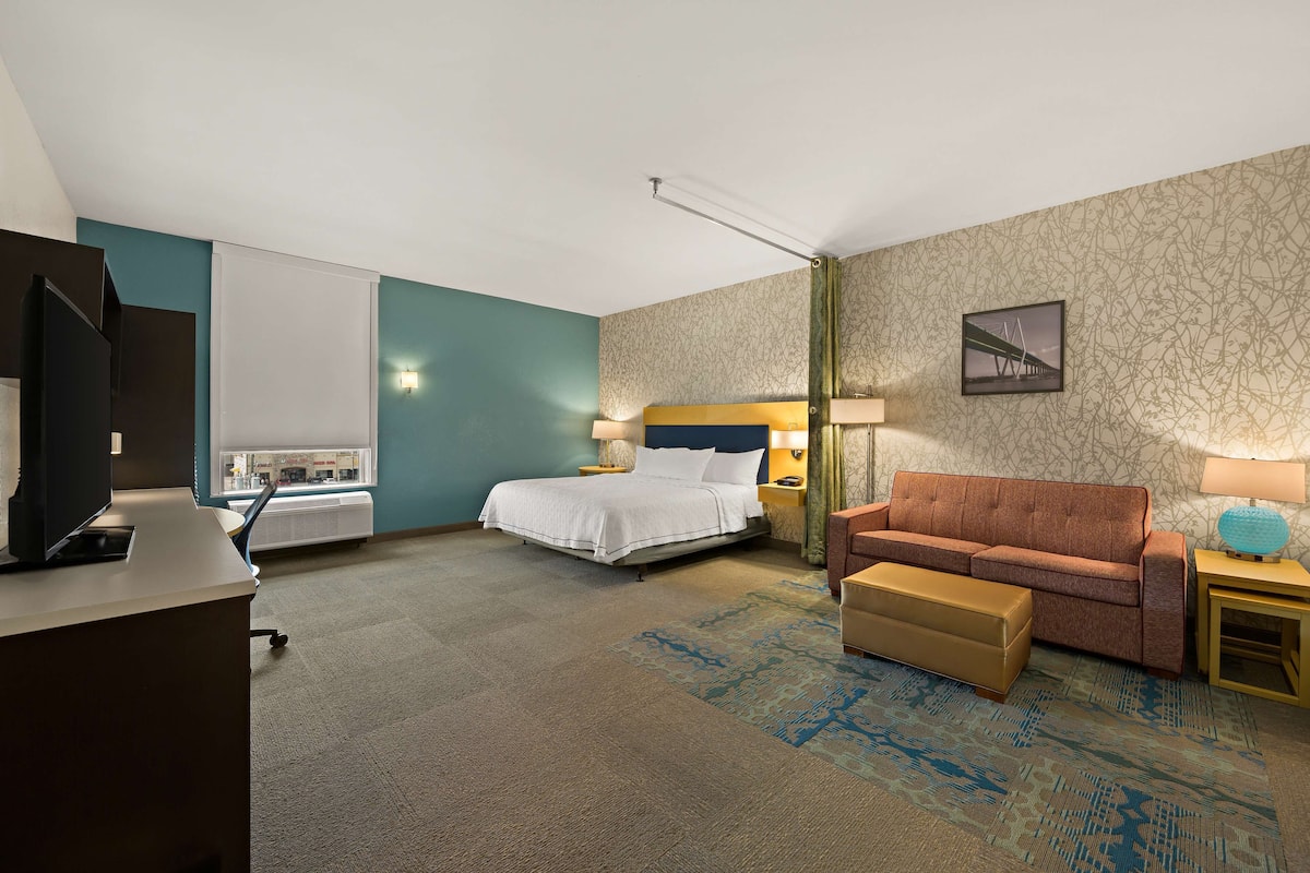 A hotel room with a bed, a desk, a couch, and a small table.