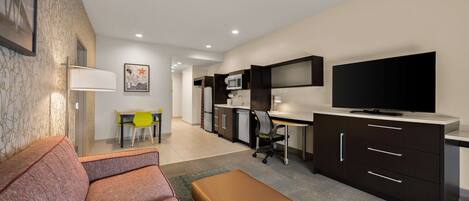 A modern living room with a sofa, ottoman, and a dining area with a table and chairs.