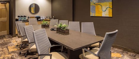 Un salón de conferencias con una larga mesa, seis sillas y una estación de café.