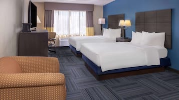 Une chambre d’hôtel avec deux lits, un bureau, une télévision et une chaise.