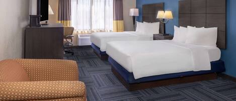 Une chambre d’hôtel avec deux lits, un bureau, une télévision et une chaise.