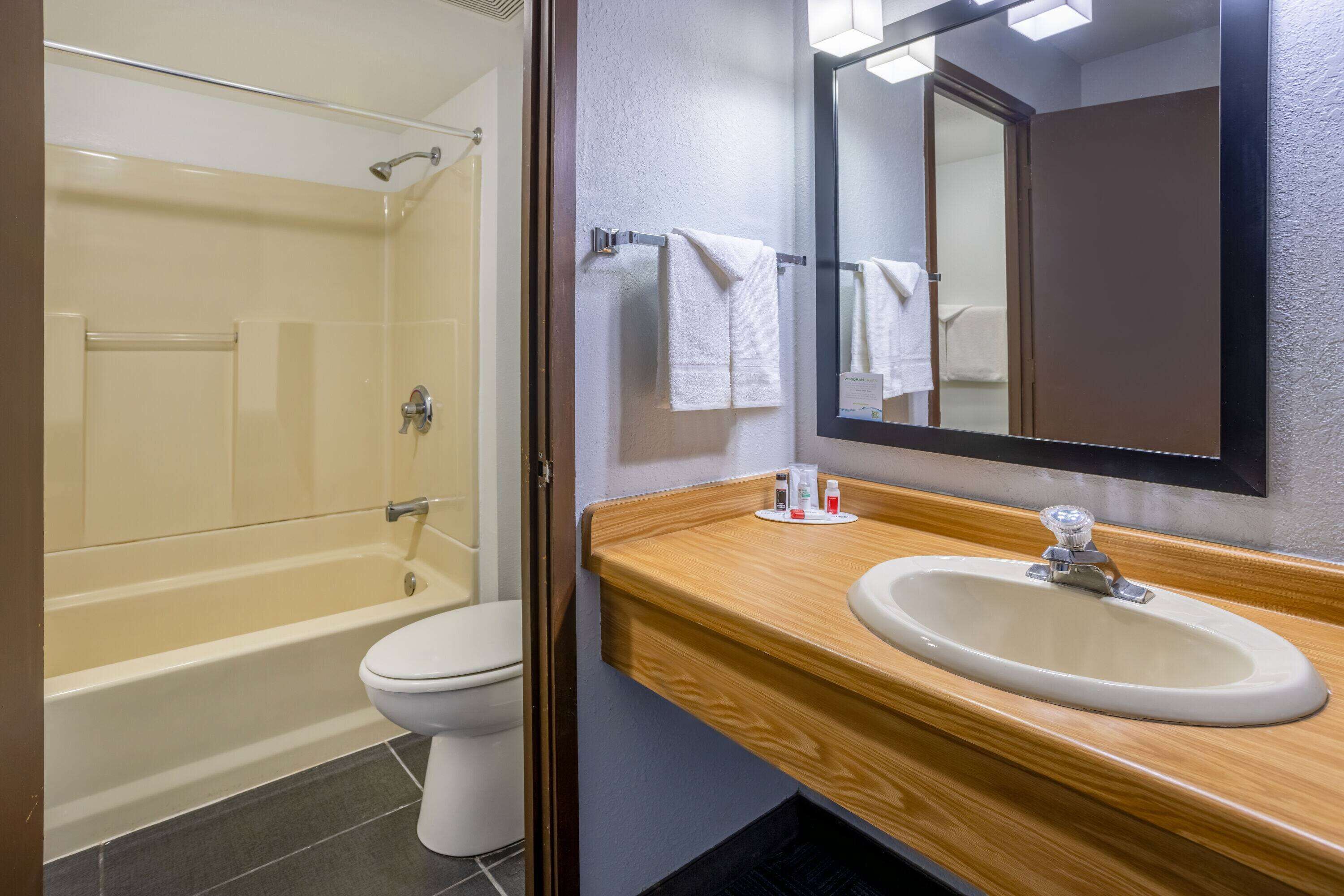 A bathroom with a bathtub, toilet, sink, and mirror.