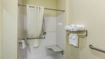 Ein Badezimmer mit Dusche, Toilette und Handtuchhalter mit Handtüchern.