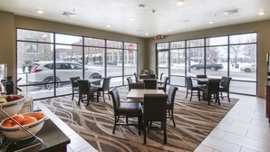Un restaurante con amplios ventanales, una zona de bufé y piso alfombrado.