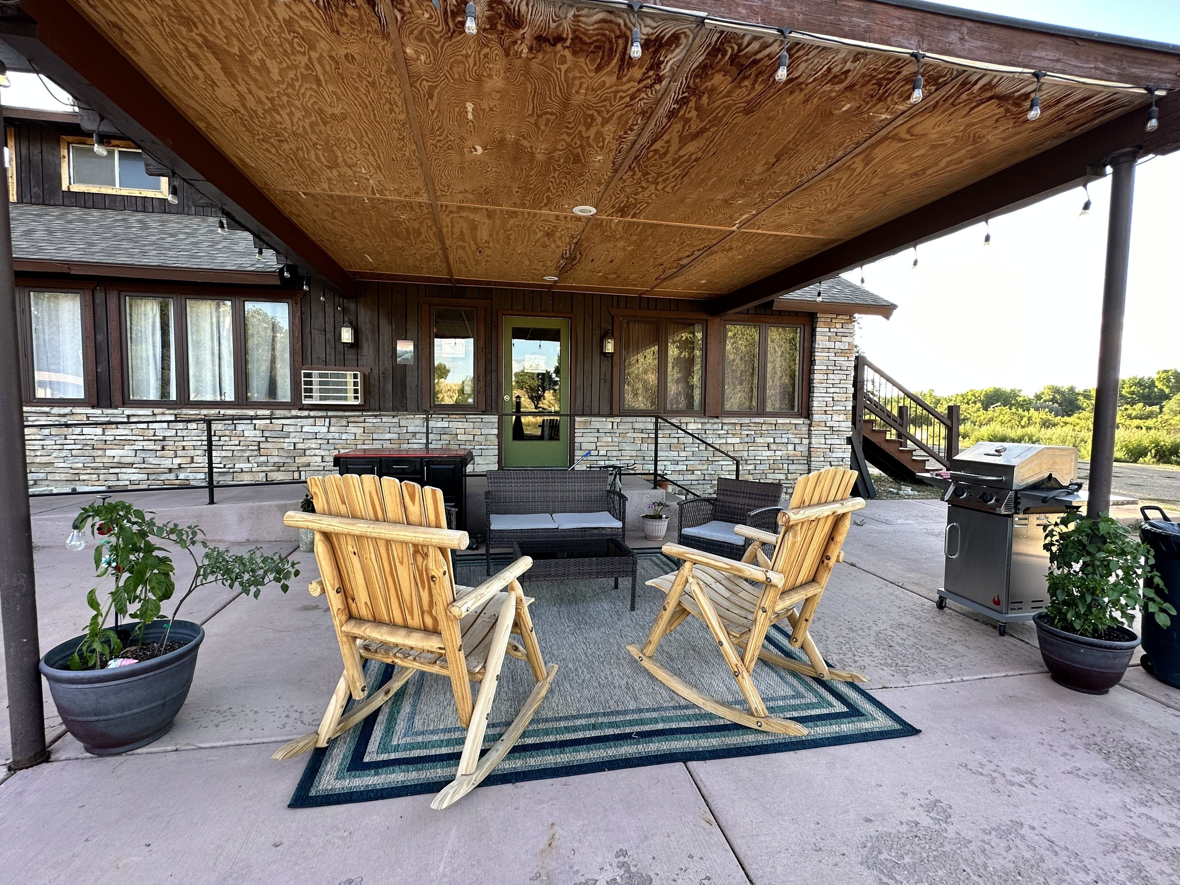 Une terrasse extérieure avec deux fauteuils à bascule, une table et un barbecue.