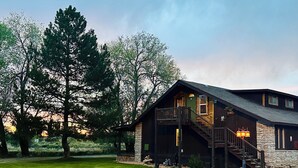 A lodge with a stone exterior, a wooden deck, and a staircase leading to the main entrance. - Moosehead Lodge & Cabins (Rangely)