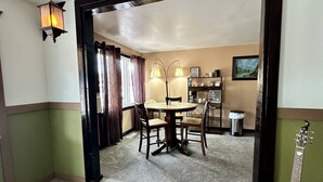 A dining area with a round table and chairs, a coffee station, and a trash can. - Moosehead Lodge & Cabins (Rangely)