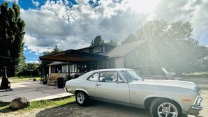 A classic white car parked in front of a modern house with a covered patio. - Moosehead Lodge & Cabins (Rangely)