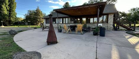 A covered outdoor seating area with stone walls and a wooden deck, featuring outdoor furniture and a large planter.