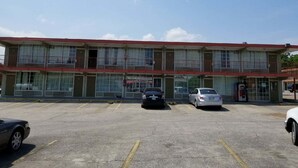 Un motel à plusieurs étages, avec un toit rouge et de grandes fenêtres. Plusieurs voitures sont garées sur le parking.