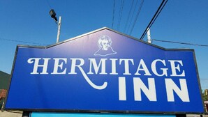 Une enseigne pour l’hôtel Hermitage, avec un logo bien visible et la silhouette d’une personne.