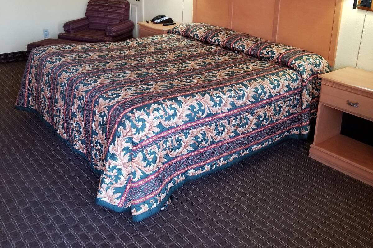A hotel room with a large bed, two bedside lamps, a chair, a desk, and a door.
