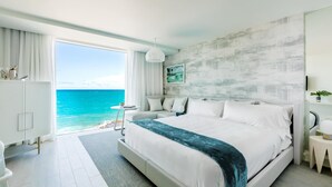 A modern bedroom with a large bed, a view of the ocean, and a minimalist decor.
