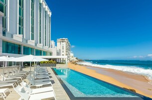 Un resort con zona de piscina, vistas a la playa y arquitectura moderna.