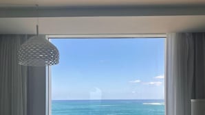A room with a large window offering a view of the ocean.
