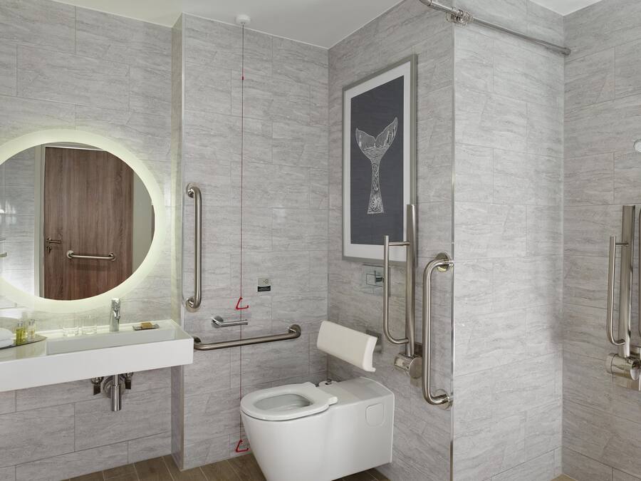Un baño moderno con un espejo redondo, un inodoro y una zona de ducha.