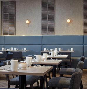 A modern dining area with booths and tables, equipped with white tableware and glasses.
