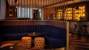 A modern bar area with a curved seating arrangement, pendant lighting, and a bar counter with shelves of bottles.