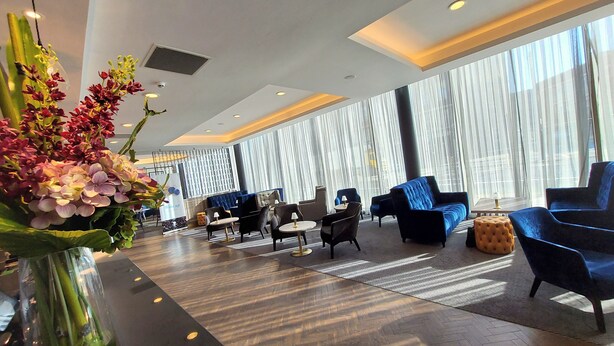 A modern lobby with a mix of seating options, including sofas and armchairs, arranged around a central coffee table.