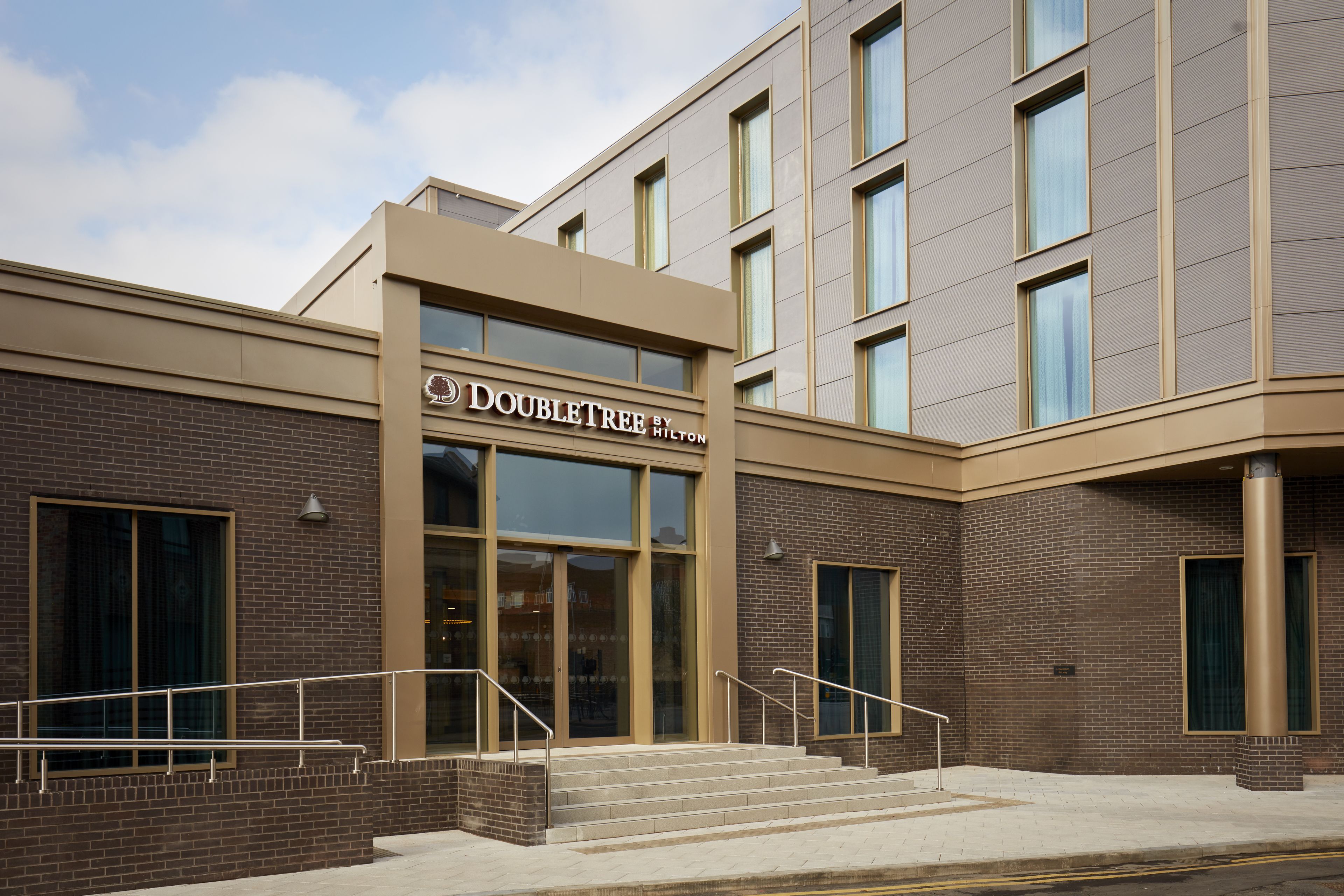 A DoubleTree by Hilton hotel with a modern facade, large windows, and a brick exterior.