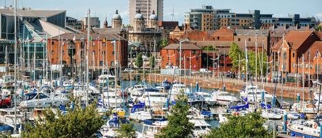 A marina with numerous boats docked, surrounded by buildings with red brick facades and modern architecture.
