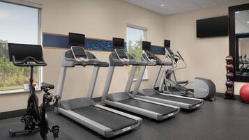 Ein Fitnessstudio mit Laufbändern, einem Ergometer und Trainingsbällen.