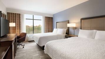 A hotel room with two beds, a desk with a television, and a chair.