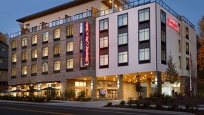 A multi-story hotel with a prominent 'Hampton Inn & Suites' sign, large windows, and a welcoming entrance with outdoor seating. - Hampton Inn & Suites Seattle/Renton (Renton)