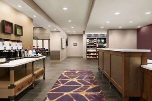 Un vestíbulo de hotel con mostrador de recepción, estación de café y minibar.