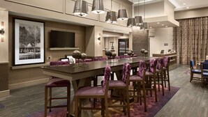 A spacious dining area with a long table, multiple chairs, and pendant lighting. - Hampton Inn & Suites Seattle/Renton (Renton)
