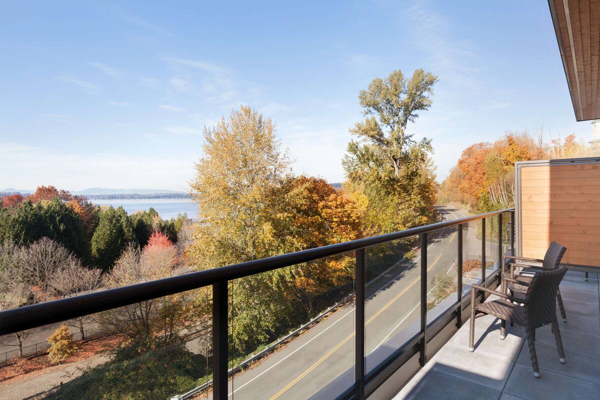 A balcony with a view of a road and autumn trees.
