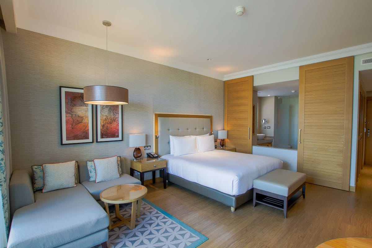 Ein Hotelzimmer mit einem großen Bett, einer Couch, einem kleinen Tisch und einem Spiegel.